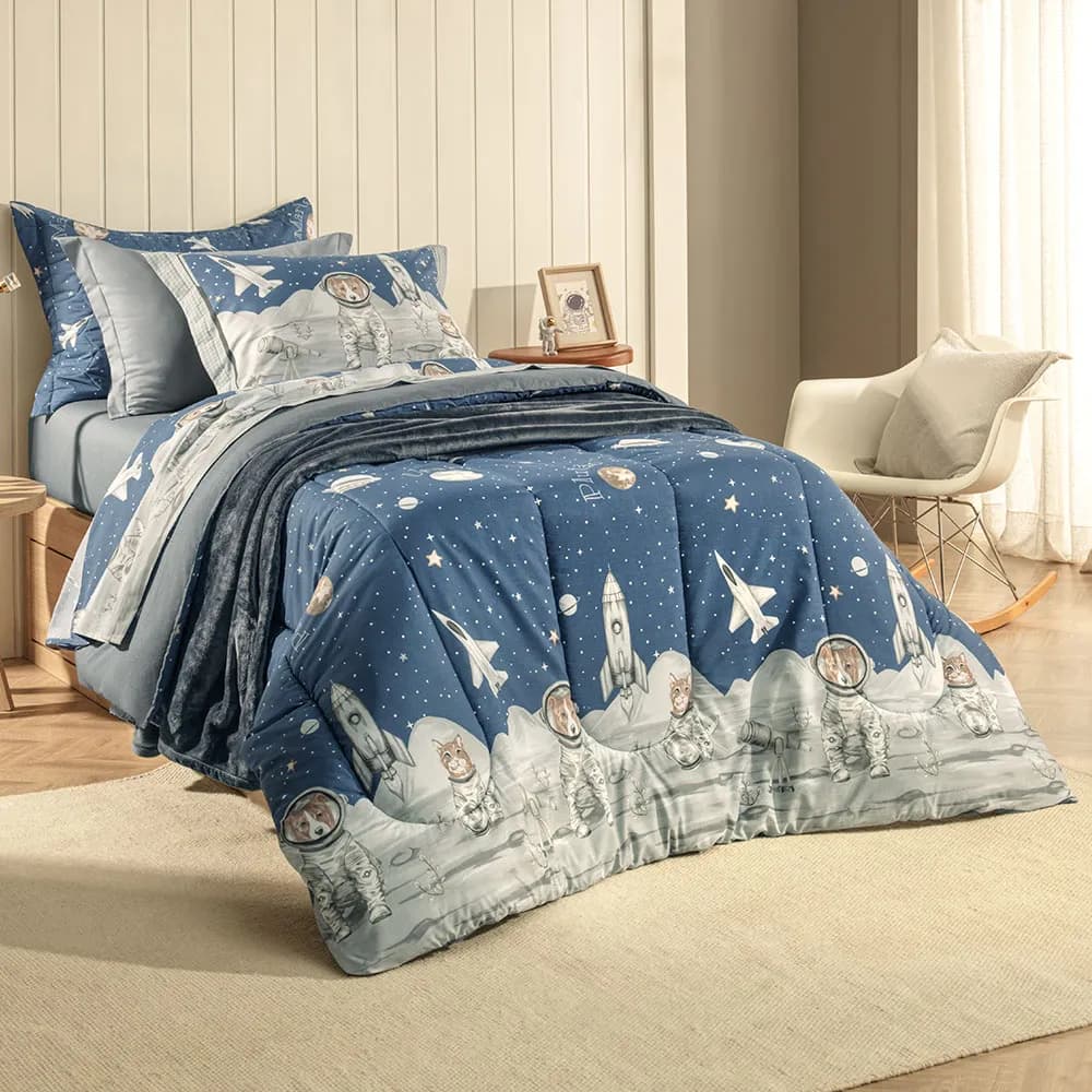 Cama arrumada com jogo de cama azul estampado com foguetes e astronautas